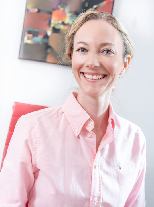 Dr. Kathrin Jennerwein in rosa Bluse lächelt freundlich in einer Arztpraxis